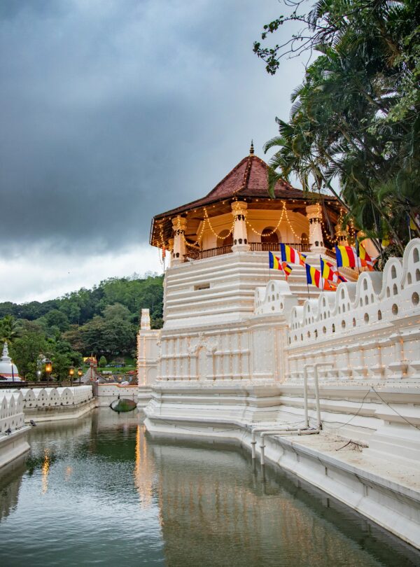 Beautiful view of a sacred temple reflecting in the river, surrounded by lush greenery, under a moody sky in Sri Lanka.